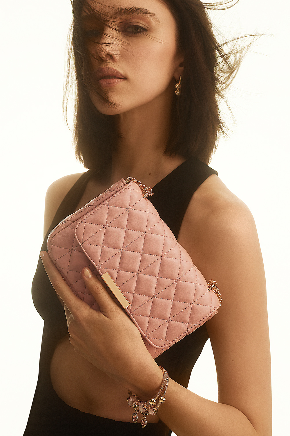 Rosa väska med quiltad design och guldfärgad axelrem