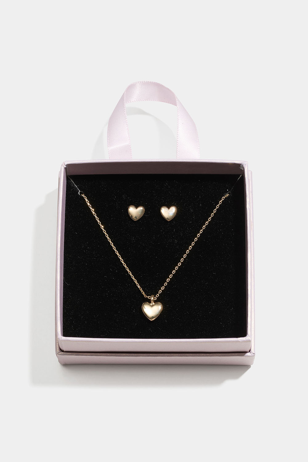 Guldfärgat smyckesset med hjärtan i presentask