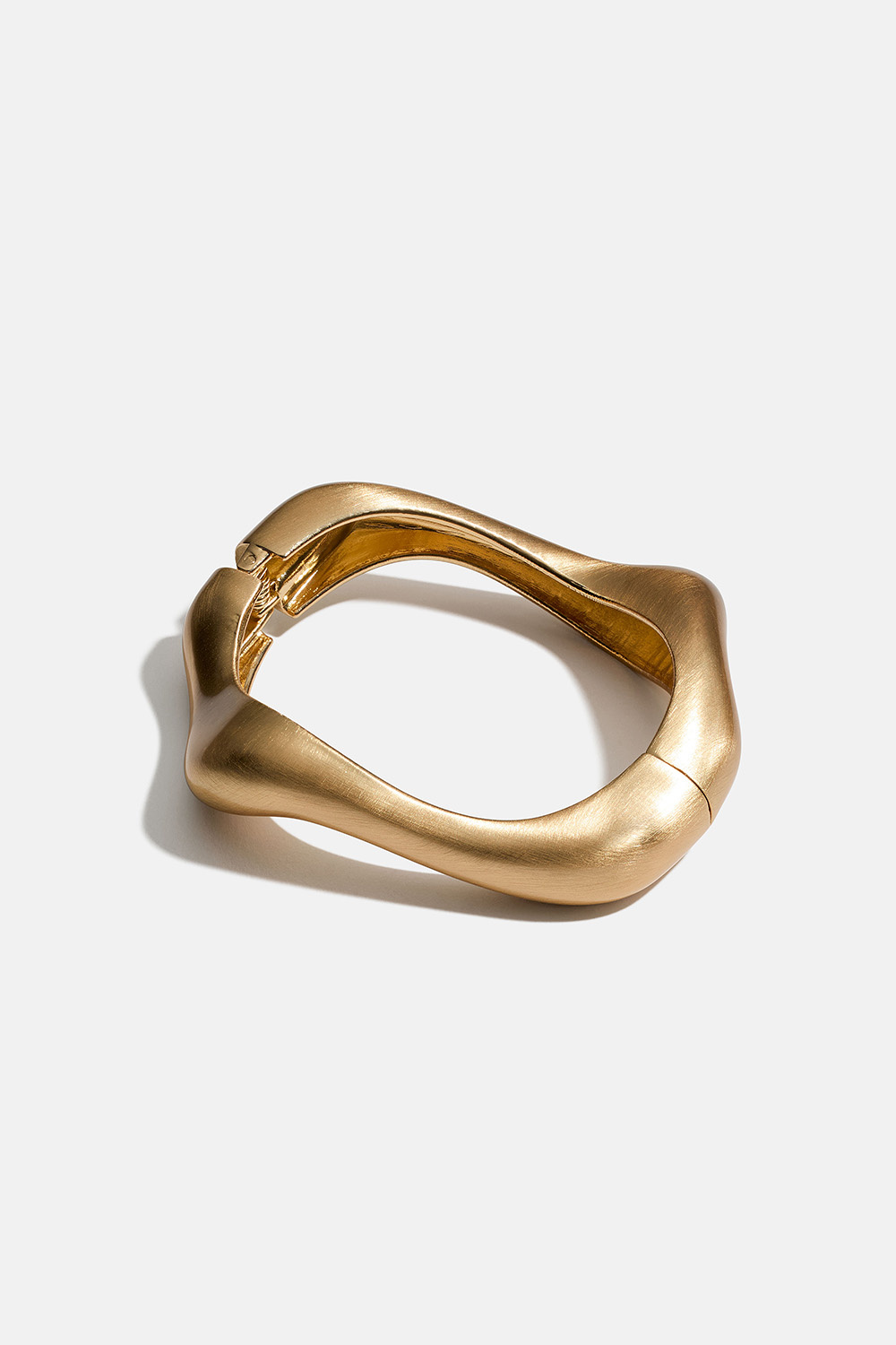 Guldfärgat bangle-armband i vågform och borstad yta