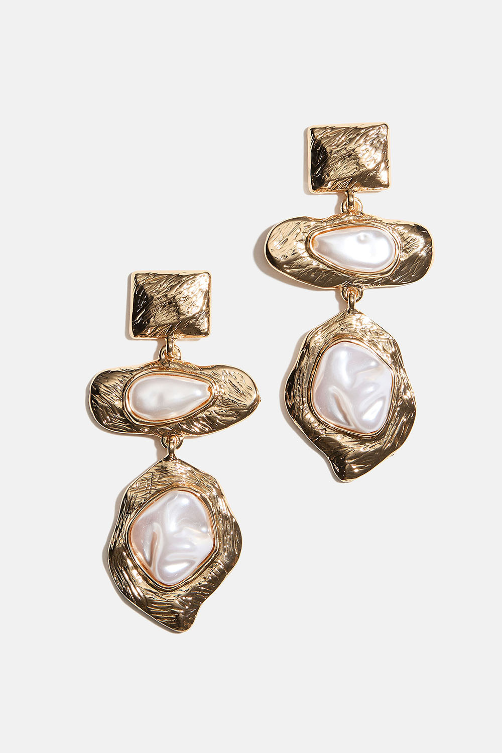 Guldfärgade örhängen med vita pärlor i organisk former