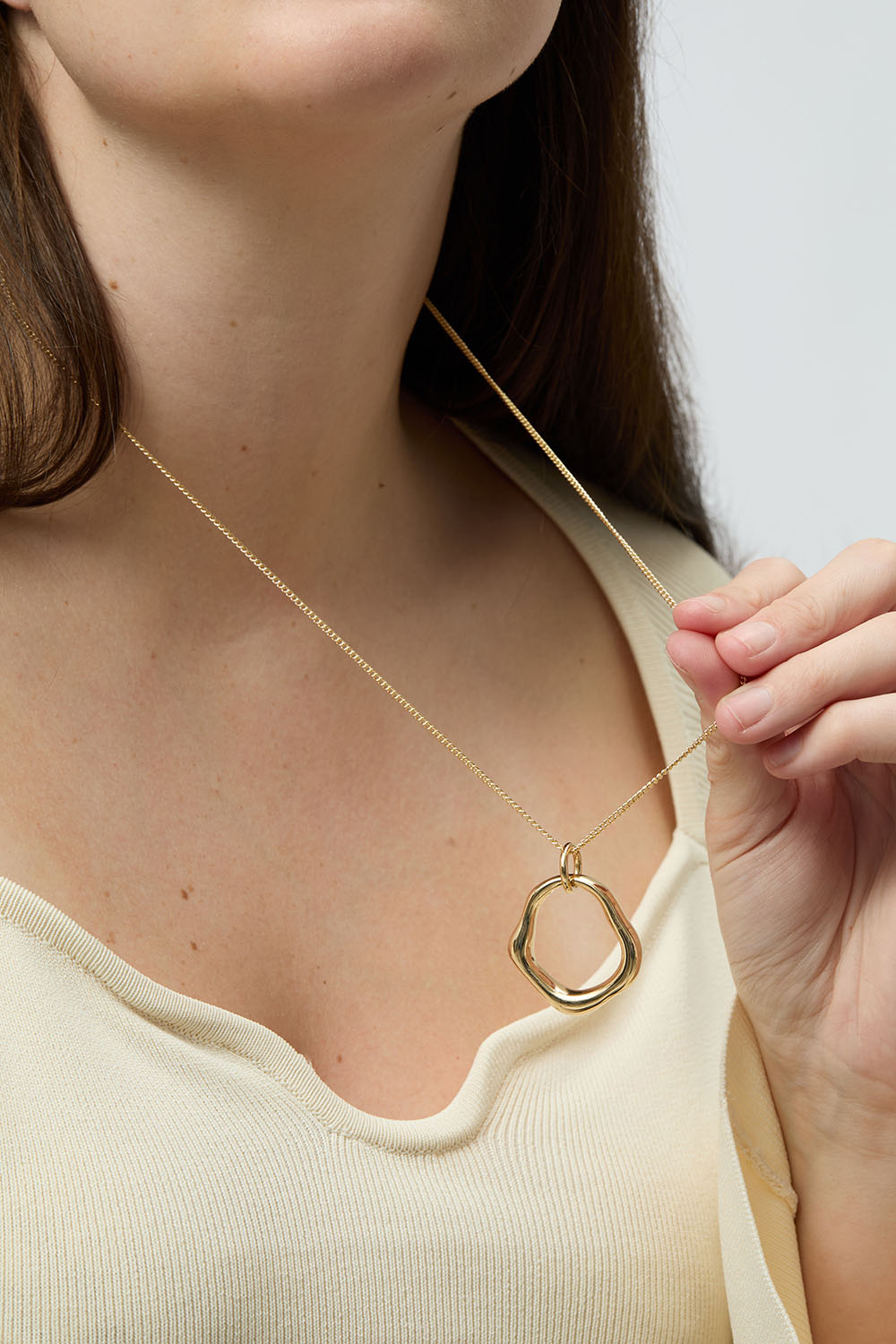 Guldfärgat halsband med runt hänge i organisk form